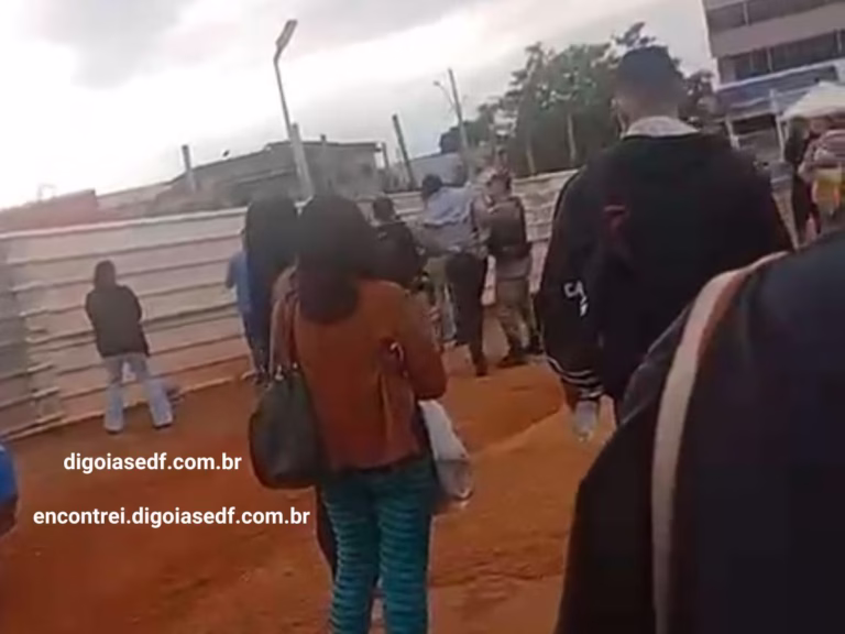Pessoas olhando dois policiais conduzido o homem algemado até a viatura do lado de fora do Hospital Estadual de Formosa.