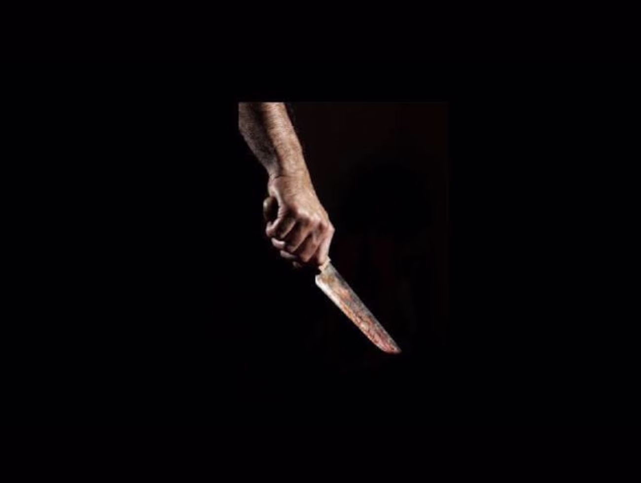 Na imagem Ilustrativa Braço de homem segurando a faca no escuro.