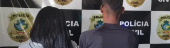 Uma mulher de longos cabelos pretos e jaqueta cinza e um homem de camisa preta posam de costas para a câmera contra uma parede quadriculada em preto e branco. ​A parede é composta por um padrão repetitivo: quadrados pretos com o texto "POLÍCIA CIVIL" e quadrados brancos com um brasão dourado que também diz "POLÍCIA CIVIL GO" (que significa Polícia Civil de Goiás). ​A imagem mostra os dois indivíduos sendo detidos e levados à delegacia.