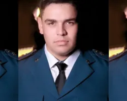 Capitão Leandro Franco é promovido no Corpo de Bombeiros após trajetória de destaque no Nordeste Goiano 6 Montagem fotográfica repetindo o mesmo homem em três seções verticais lado a lado. Ele aparece em um retrato formal de estúdio, com uma expressão séria, olhando diretamente para a câmera. Está vestindo uma farda oficial azul-petróleo de gala, camisa social branca por baixo e uma gravata preta escura. O fundo é escuro.