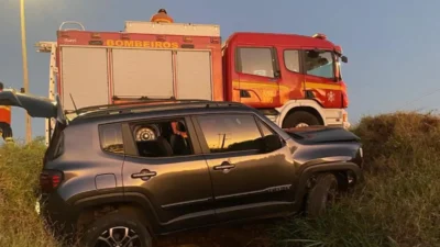 Acidente na DF-001 carro caído em vala, ao lado caminhão do Corpo de Bombeiros prestando atendimento.