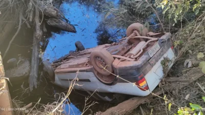 Acidente em estrada rural de Formosa: Carro cai de ponte e deixa 2 feridos 1 Carro caído em corrego após sai sa pista, na imagem é possível ver o carro com as rodas pra cima, corrego com água e vegetação.