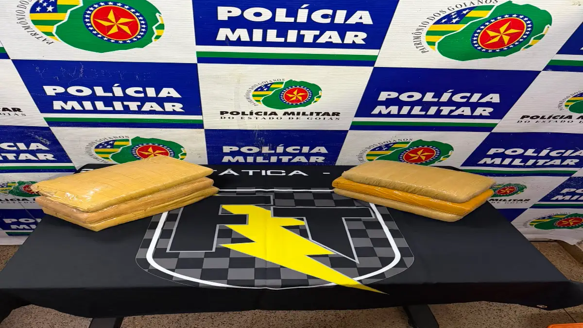 Drogas apreendidas na BR-020 em Formosa, a força tática fez a abordagem e encontrou a droga, na imagem está sobre a mesa com banner ao fundo escrito Polícia Militar.